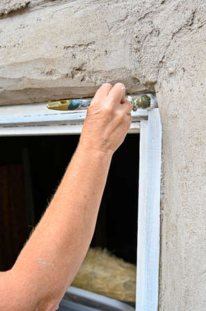 woman painting white on window frame on old barnの写真素材