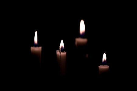 four candles burning i dark black room