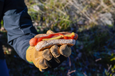 man holding grilled hotdag outdoor in forestの写真素材
