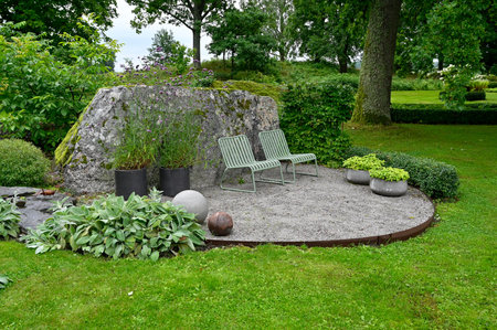 Two metal chairs standing ner big stone in gardenの写真素材