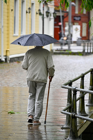 One old man with umbrella and cane Orebro Sweden august 9 2023のeditorial素材
