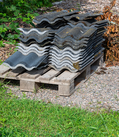 Black roof tiles piled up on wooden euro palletの写真素材