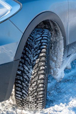 close up of studded tires on car standing on snowの写真素材