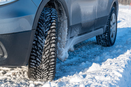 close up of studded tires on car standing on snowの写真素材