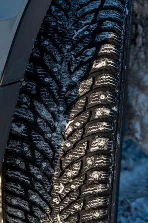 close up of studded tires on car standing on snowの写真素材