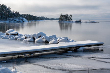 Stone barrier and wooden jetty covered in snowの写真素材