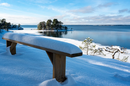 Wooden bench covered in snow near lake Vattern Motala Swedenの写真素材