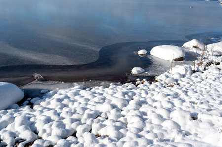 Stones on beach covered in white snowの写真素材