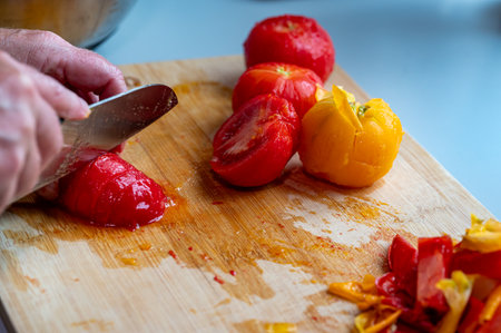 Woman peeling ang cutting fresh tomatoes in kitchenの写真素材