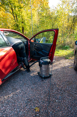 woman vacuuming car inside with coarse vacuum cleanerの写真素材