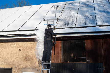 Man removing snow from solar panels on roofの写真素材