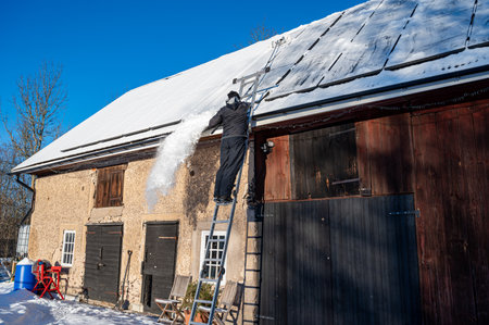 Man removing snow from solar panels on roofの写真素材