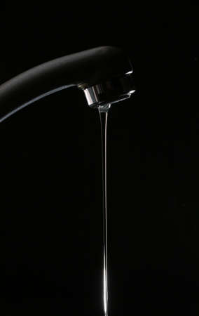 Water flowing from a tap on a black background.