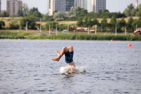 A young man jumping into the water on a sunny dayの写真素材