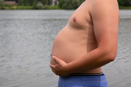 Fat man with big belly on the background of the river. The concept of obesity.の写真素材