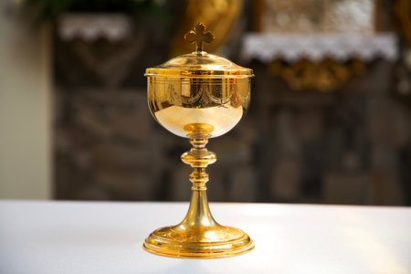 Golden chalice on a white table in a Catholic Church.