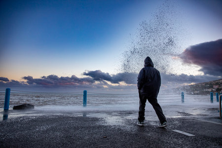 Man standing near a splashing waveの写真素材