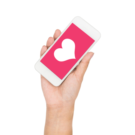 Girl hand holding mobile phone display heart on pink screen isolated on whiteの写真素材