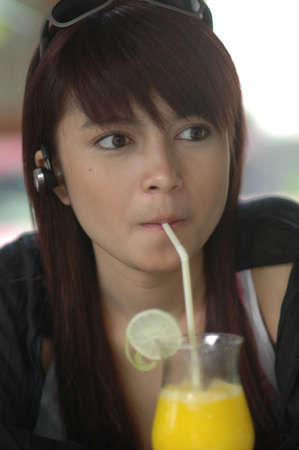 young lady drinking orange juiceの写真素材