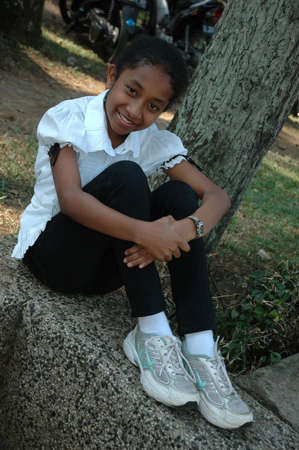little girl sit down beside the treeの写真素材