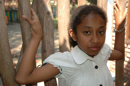little girl stand up beside wood barの写真素材