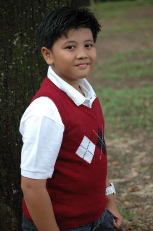 young boy stand up beside the treeの写真素材