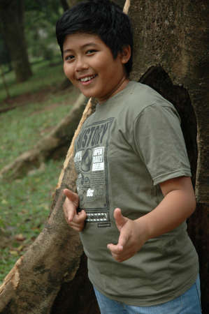 little boy stand up beside the tree
