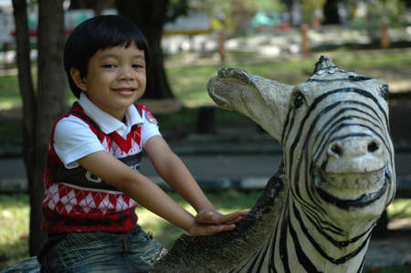 little boy sit down on zeebra statueの写真素材