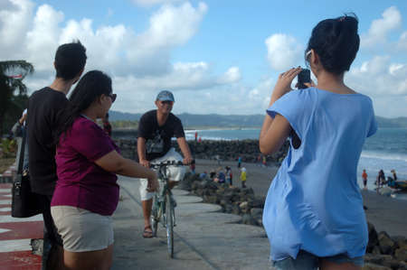 pangandaran, indonesia-july 16, 2011  man riding a bike at pangandaran beach shore, west java-indonesia のeditorial素材