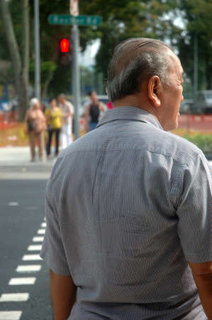 Singapore, Singapore - January 18, 2014: Old man waiting for red light to get across the road.のeditorial素材