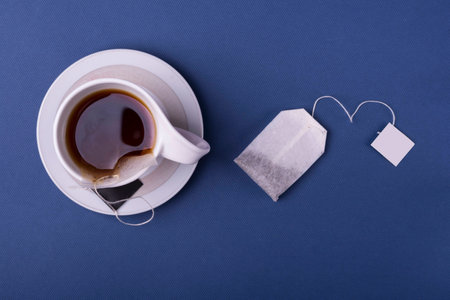 Porcelain white cup tea with one teabag on dark blue background. top view studio shotの写真素材