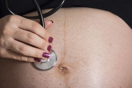 Pregnant woman using stethoscope to listening her baby heart rate sound, mother listen her fetus...