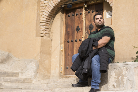 Young man seated in front of decorated wooden door, Masuleh Villageの写真素材