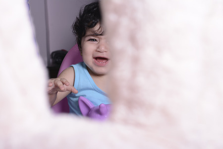 Little baby girl on unicorn swing crying for teddy bear dollの写真素材