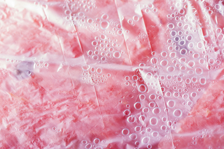 Background texture of a fresh juicy pink watermelon under plastic cover with condensation bubblesの写真素材