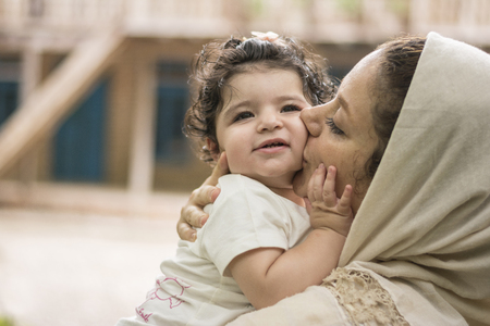 Young mother kissing her little girl child, parenting, love and care conceptの写真素材