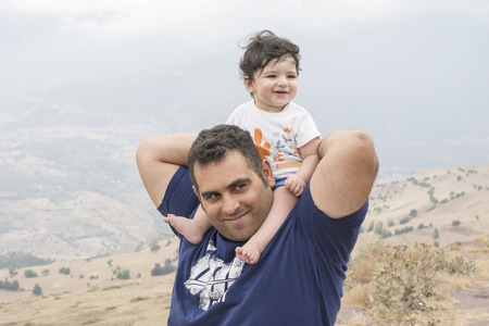 Portrait of a happy father carrying her girl on shoulder, enjoying in natureの写真素材