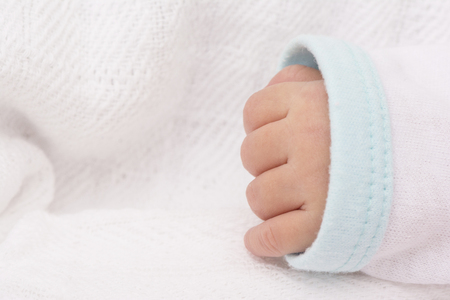 Newborn baby hand, closeup view on white clothの写真素材