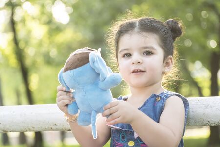 Close up Little girl portrait holding a blue elephant doll in hands, childhood memories conceptの写真素材