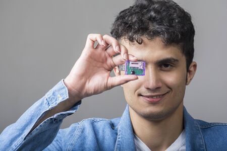 Young man holding a USB connectivity for standard SD memory cards with  right hand in front of his...
