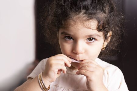 Little girl portrait with chocolate tablet in hands, side lighting の写真素材