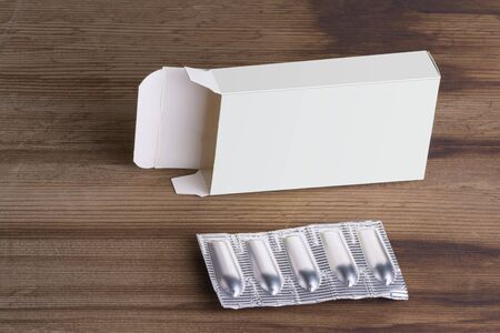 Suppositories loaf and an empty box on wooden table background, editable mock up template ready for...