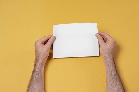 Male hand holding a letterhead paper envelope, editable mock up template for your design, selection...