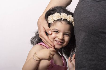 A young beautiful two years old girl portrait with her pregnant mother belly, Parents and kids...