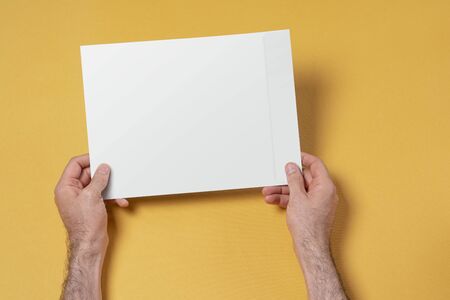Male hands holding an A4 paper envelope, editable mock up template for your design, selection path...