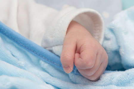 Newborn baby hand peacefully sleept at bed, fist macro shot