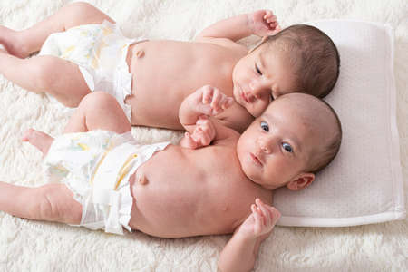 One month newborn twin babies resting on bed, close up top viewpoint shot