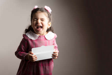 Surprised Little girl holding a small gift box in hands, editable mock-up series template ready for your design, box selection path included.の写真素材