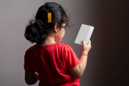 Little girl holding a small box in hands, editable mock-up series template ready for your design, box selection path included.の写真素材