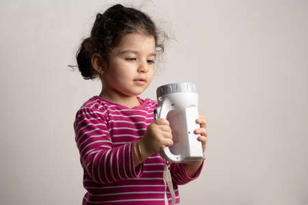 Little girl playing with a torch light childhood curiosity concept